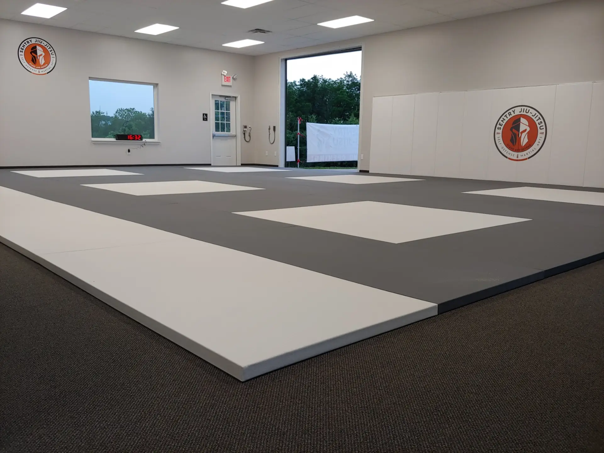 Clean professional mats and the Sentry Jiu-Jitsu logo wall inside the academy